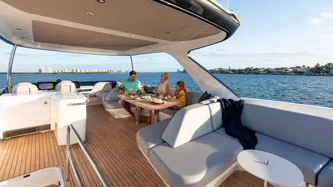 Princess F65 flybridge with a helm, dining table and L shaped settee under the hardtop