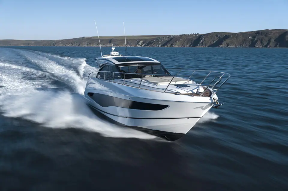 Princess V50 seen from the bow quarter running fast along a rocky coast