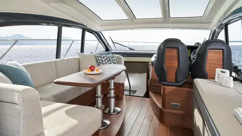 Princess V50 main deck saloon with a sofa, dining table and twin helm seats forward