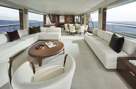 Princess X95 main saloon with white sofas, a round coffee table and the dining area beyond