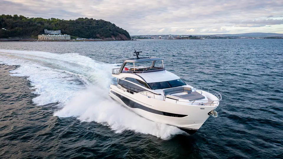 Princess Y85 running at speed seen from above the bow quarter off a green headland