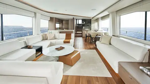 Princess Y85 main saloon with white sofas, a round coffee table and the dining area beyond