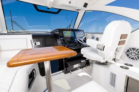 Pursuit OS 325 Offshore bridge deck with helm seat, dash electronics and a teak table under the hardtop