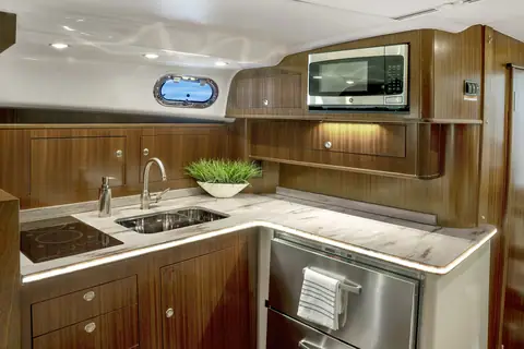 Pursuit OS 385 Offshore cabin galley with wood cabinets, sink, cooktop and microwave