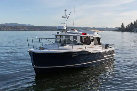 Ranger Tugs R-23 with a navy hull seen from the bow quarter on calm water