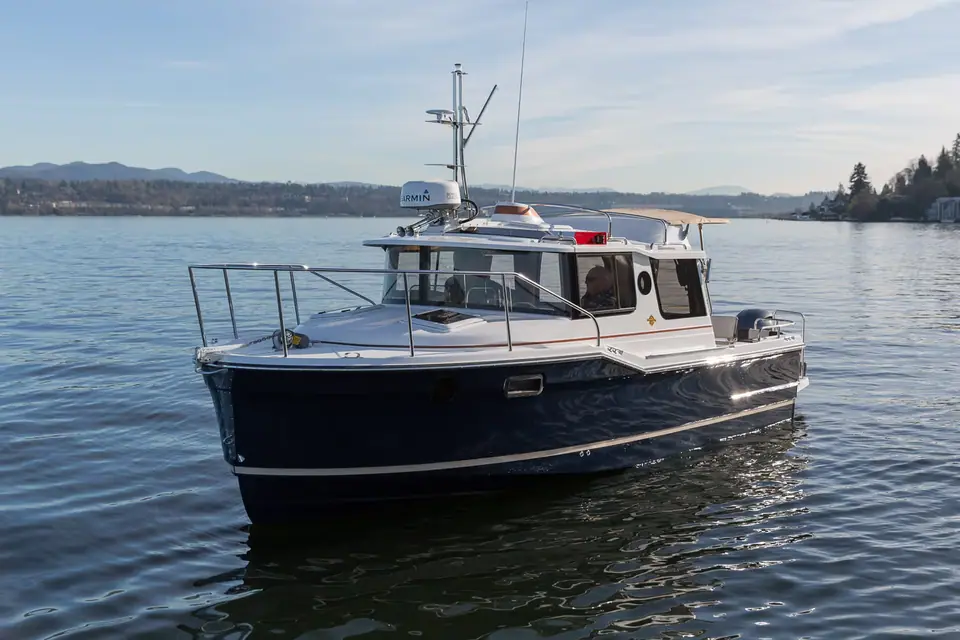 Ranger Tugs R-23 with a navy hull seen from the bow quarter on calm water