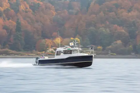 Ranger Tugs R-25 running at speed past a hillside of autumn trees