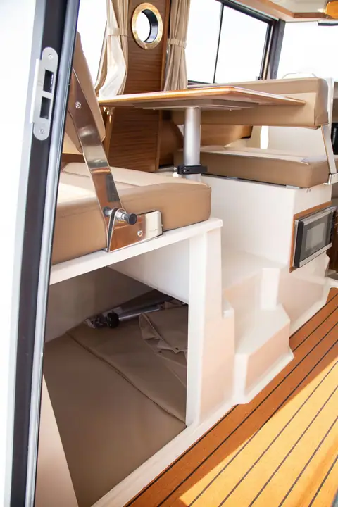 Ranger Tugs R-25 cabin dinette with a teak table beside the pilothouse windows