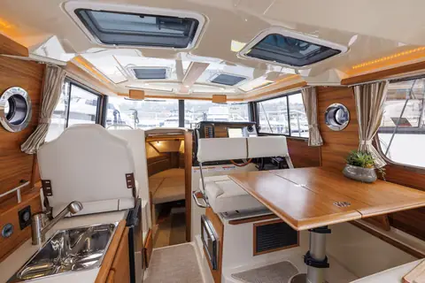 Ranger Tugs R-27 pilothouse with a teak dinette table, skylights and helm forward