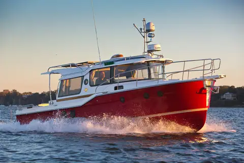 Ranger Tugs R-29 S with a red hull running at speed in profile at sunset