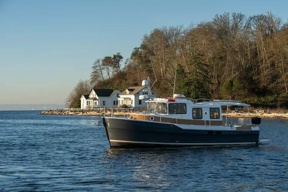 Ranger Tugs R-31 S sedan version cruising past a wooded point with white houses
