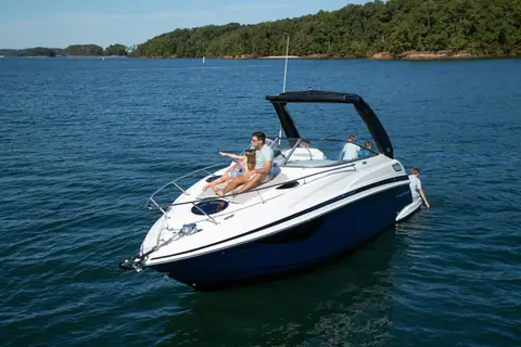 Regal 28 Express cruiser with a navy hull and bimini at rest near a wooded shore
