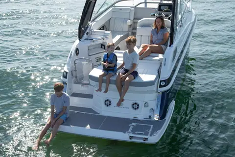 Regal 28 Express cockpit and swim platform with a family seated on the aft lounge