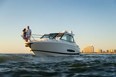 Regal 36 XO bow and hardtop with a couple standing on the foredeck at sunset
