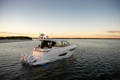Regal 38 XO seen from astern with triple outboards and guests in the cockpit at dusk