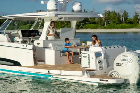Regal 43 SAV aft cockpit with family dining at the table beside the Yamaha outboards