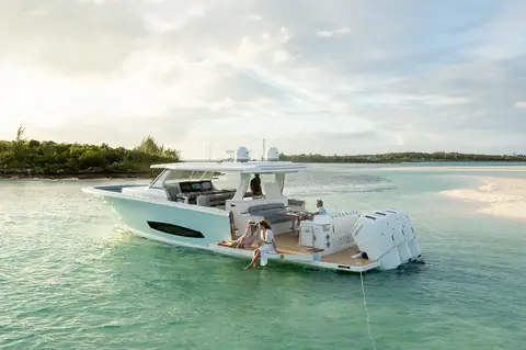 Regal 50 SAV at anchor off a beach with guests on the swim platform beside triple outboards