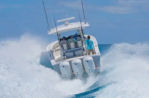 Regulator 37 seen from astern running through spray on triple outboards