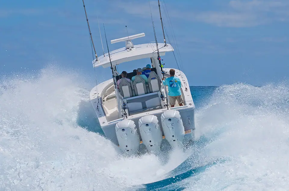 Regulator 37 seen from astern running through spray on triple outboards