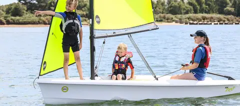 RS Zest with three young sailors aboard under the green training rig