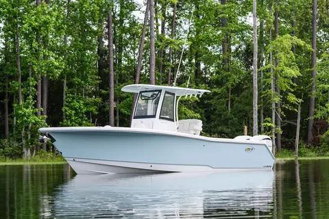 Sea Hunt Gamefish 27FS at rest near a wooded shore