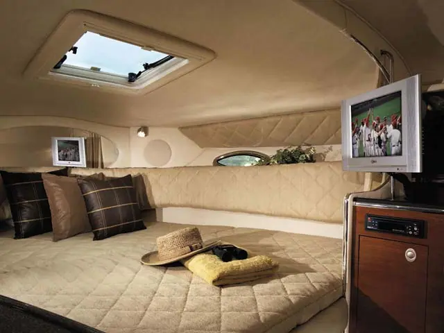 Sea Ray 290 Amberjack cabin berth with plaid pillows, a hatch and a flat screen TV