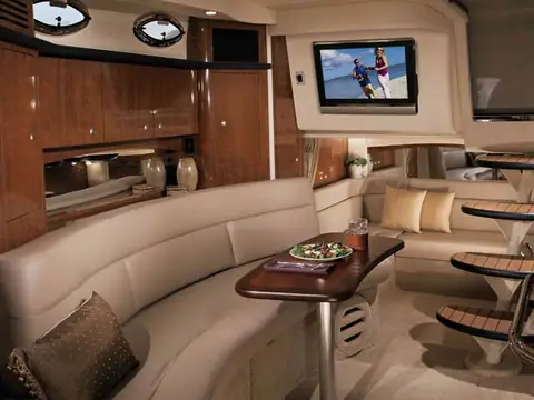 Sea Ray 340 Sundancer salon with a curved cream settee, cherry joinery and a flat screen TV