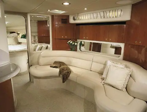 Sea Ray 380 Sundancer salon with a curved cream leather settee and cherry cabinets