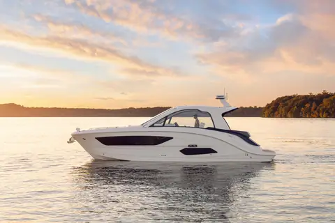 Sea Ray Sundancer 370 sterndrive model seen in port profile on calm water at dusk