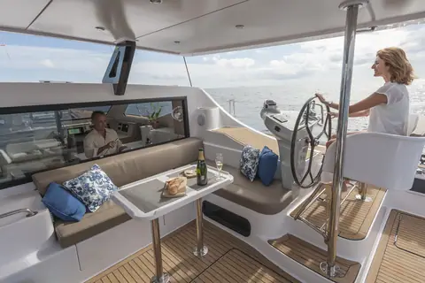 Seawind 1600 aft cockpit opened to the saloon with a helm wheel and lounge seating