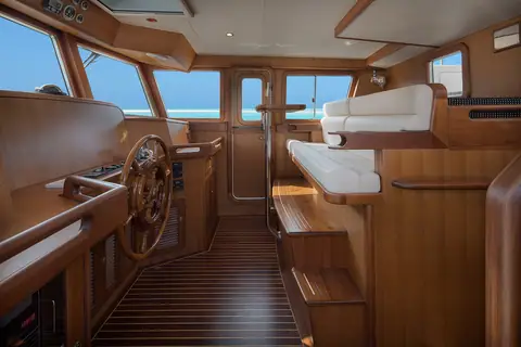Selene 49 pilothouse with a wooden wheel, teak joinery and the raised settee behind the helm