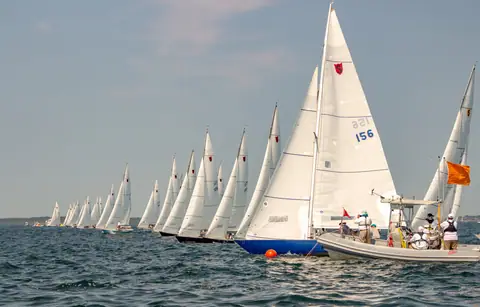 Shields one design fleet lined up at a race start beside the committee boat