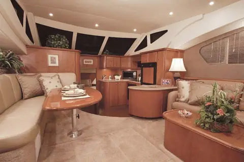 Silverton 39 Motor Yacht saloon with cherry joinery, curved settee, dinette and galley