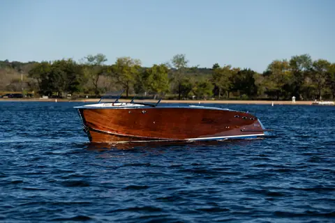 StanCraft 260 Rivelle varnished mahogany hull idling on a blue lake
