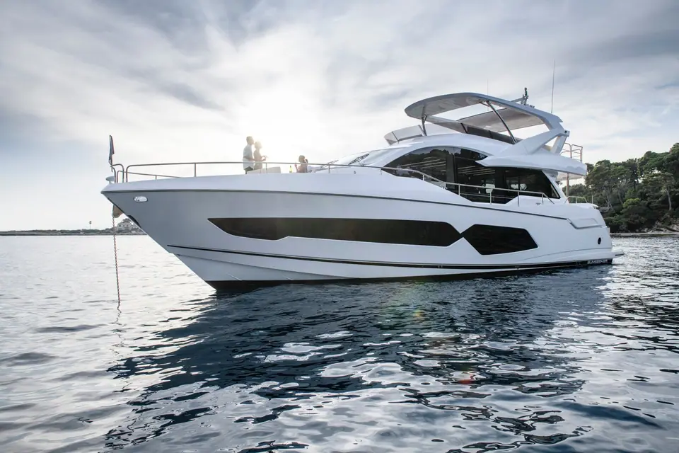 Sunseeker 76 Yacht at anchor in calm water showing its flybridge and hull windows