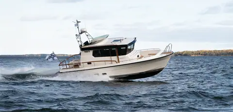 Cream hulled Targa 32 pilothouse boat planing through a chop near a wooded shore