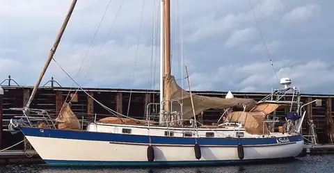 1983 Valiant 40 cutter with a blue and white hull moored in profile with sail covers on
