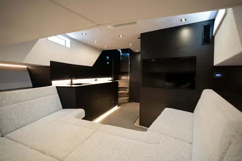 Vanquish VQ58 lower salon with a U shaped sofa, dark wood galley and wall mounted TV
