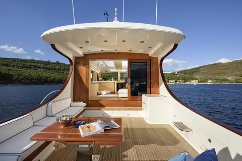 Vicem 65 Classic aft deck with teak sole, settee and table under the curved hardtop overhang