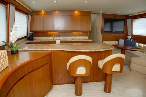 Galley of a 2008 Viking 60 Convertible with a granite counter, bar stools and teak cabinets