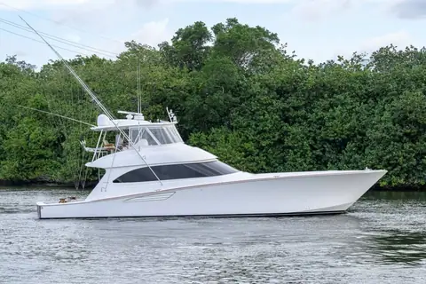 2014 Viking 70 Convertible with outriggers cruising past a wooded shoreline in profile