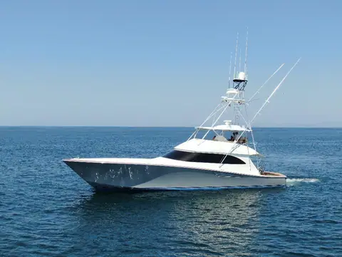 First generation Viking 70 Convertible with a tuna tower and outriggers cruising slowly on calm sea