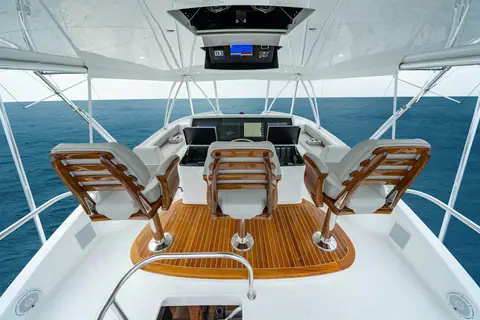 Viking 82 Convertible flybridge helm with three teak helm chairs and a console of displays