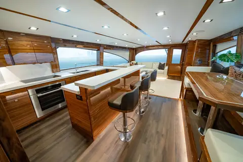 Viking 82 Convertible salon and galley with satin teak, bar stools and wraparound windows