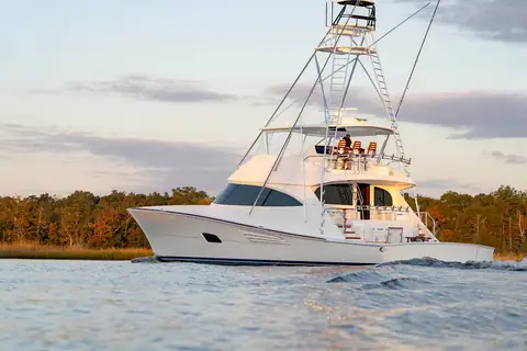 Viking 90 Convertible underway near a wooded shoreline in warm evening light