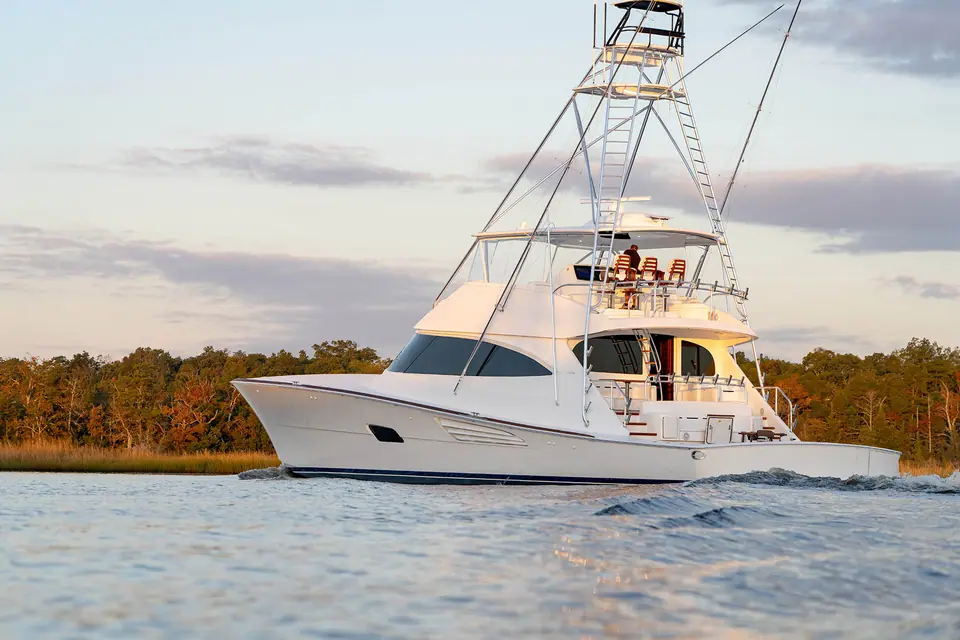 Viking 90 Convertible underway near a wooded shoreline in warm evening light