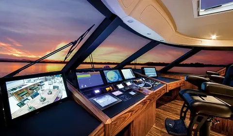 Viking 92 enclosed bridge helm with a wide console of displays and dark wood trim at sunset