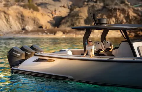 Gray Wajer 38 S with triple outboards and a T top at anchor in a rocky bay