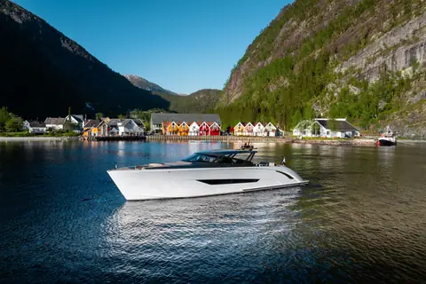 White Wajer 77 underway in a fjord past a village of colorful waterfront houses
