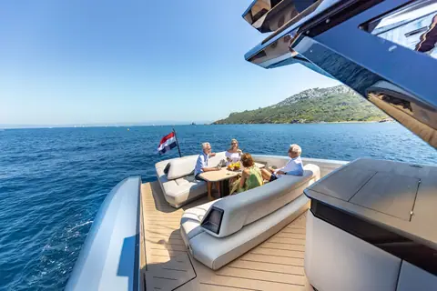 Guests at the Wajer 77 aft deck lounge and table while the yacht cruises a sunny coast